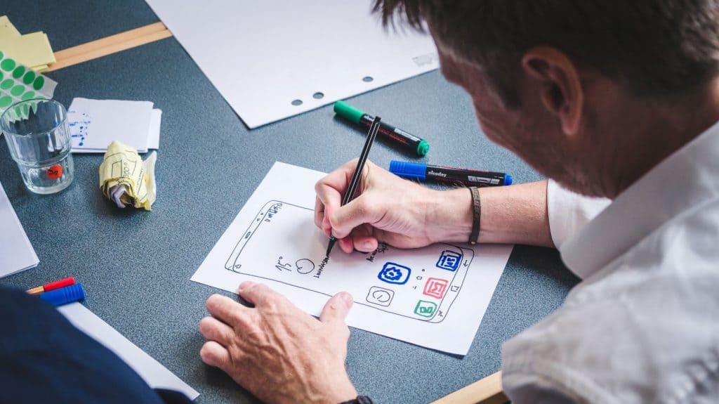 person writing a website design on a notepad