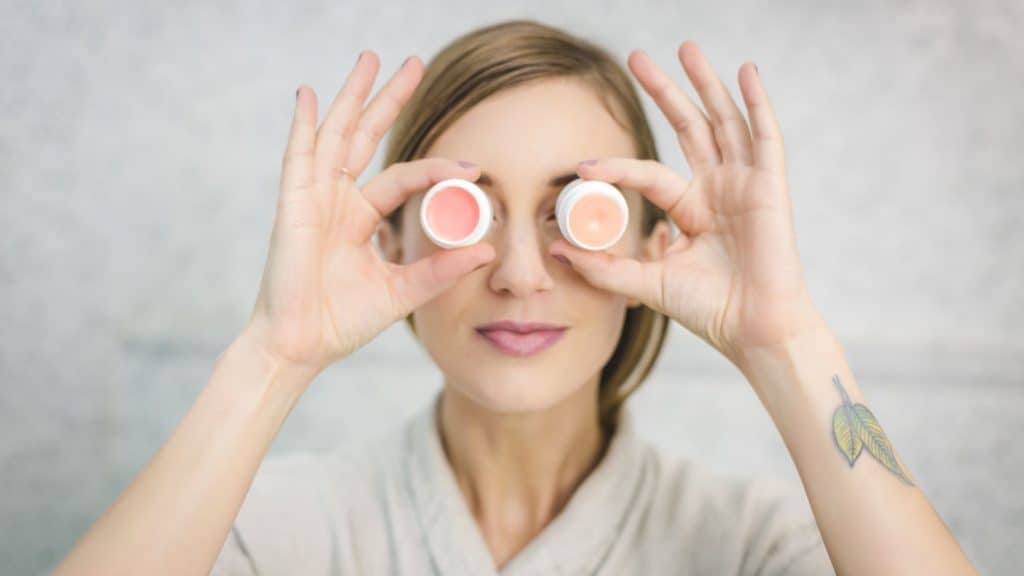 beauty - woman holding skincare products in front of her eyes