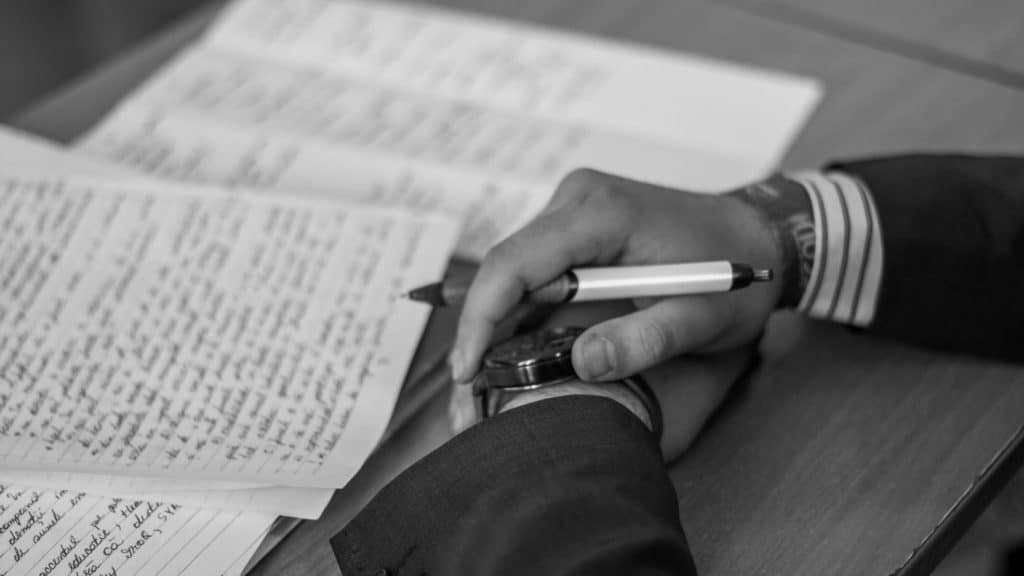 person holding a pen and writing words on the page
