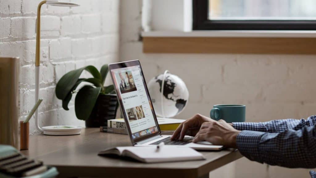 man typing a blog post on a laptop