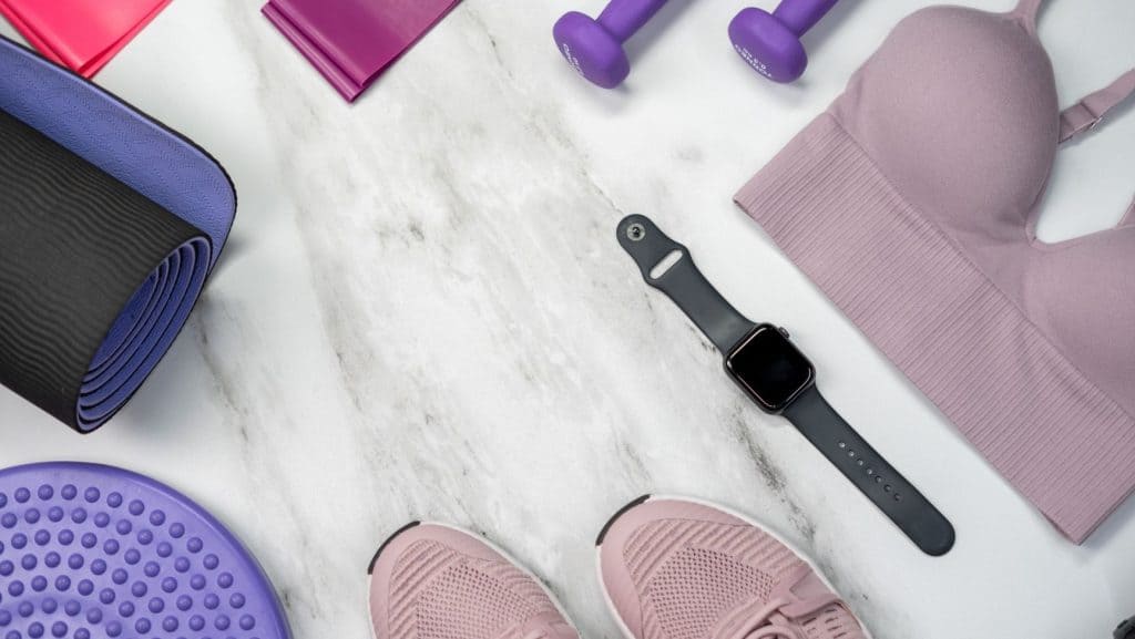 pink sports bra, black smart watch, purple dumbbells
