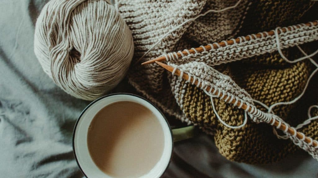 coffee mug next to knitting needles