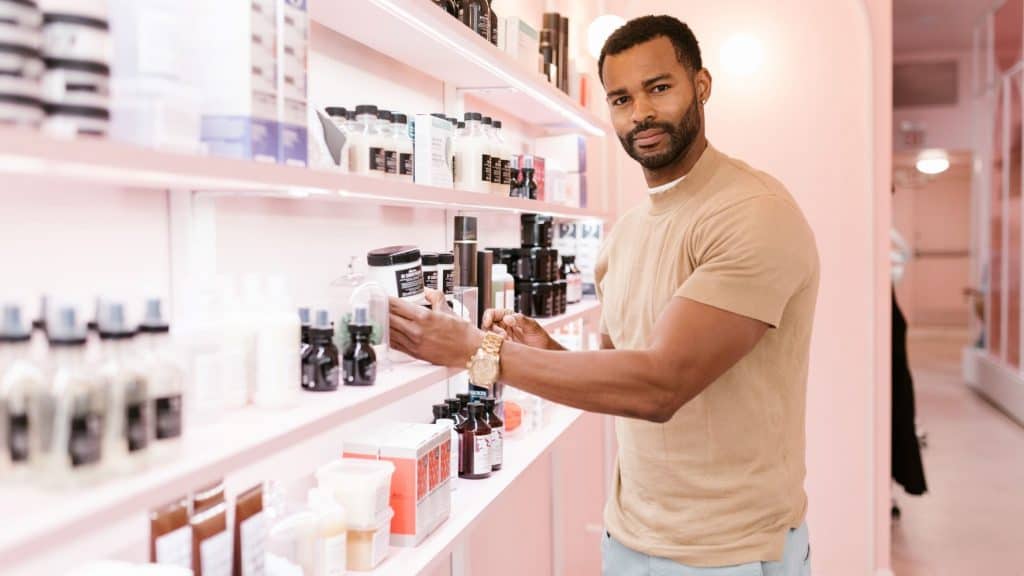 man standing next to a shelf of beauty projects