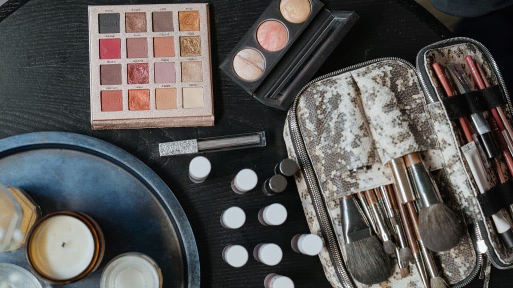 eyeshadow palette and makeup brushes on a black table