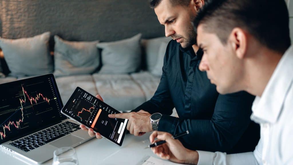 two men looking at website analytics on a laptop and tablet