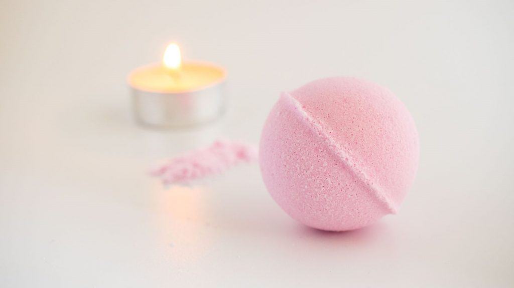 pink bath bomb and small votive candle
