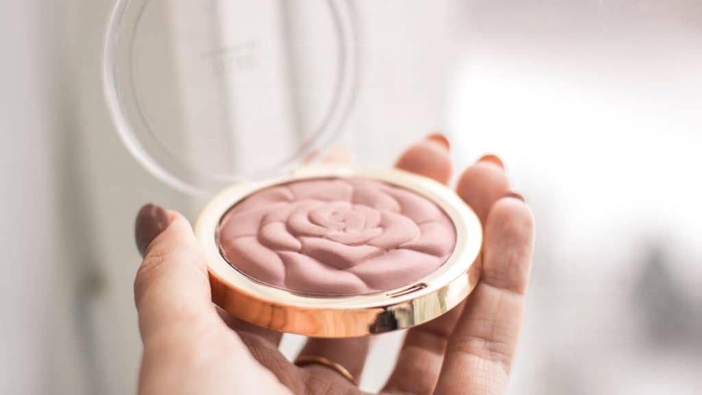 woman holding pink makeup compact