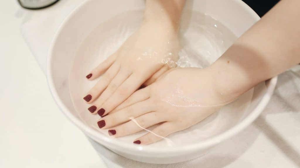 woman soaking her nails in a bowl