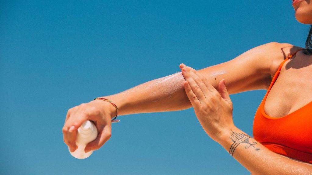 tattooed women holding a skincare packaging design in the sun