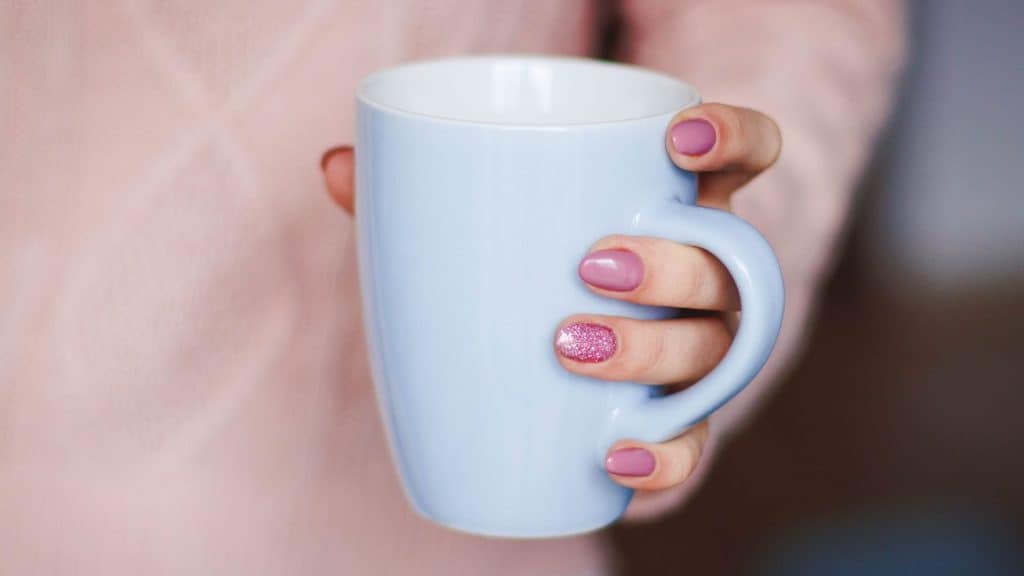 woman holding mug of white tea packaging