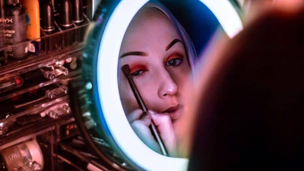 woman applying makeup in a ring light mirror