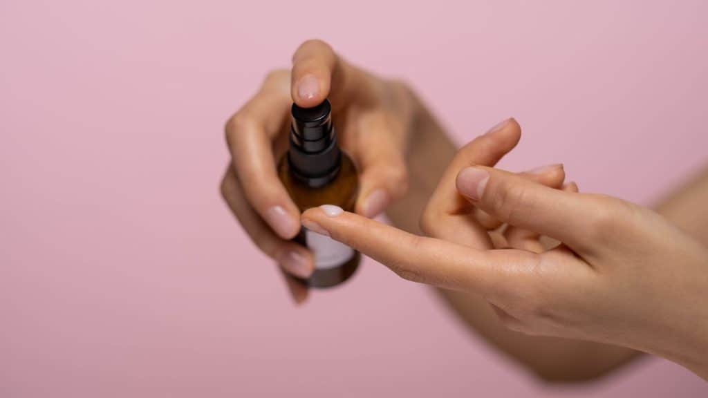 woman spraying skin care product into hand