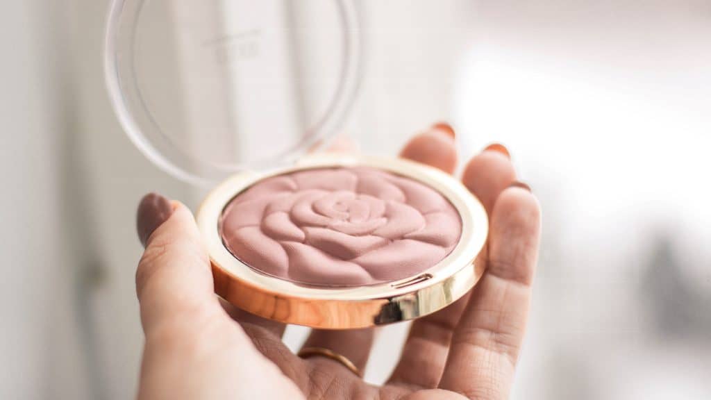 woman holding a pink blush compact as an example of makeup marketing strategies