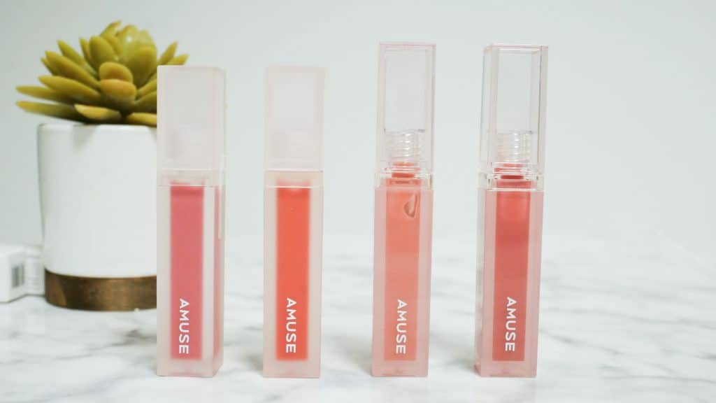 makeup packaging design for four pink lip glosses on a white table