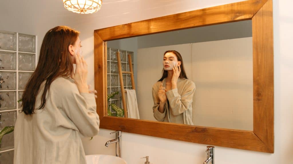 woman applying beauty products in a large mirror