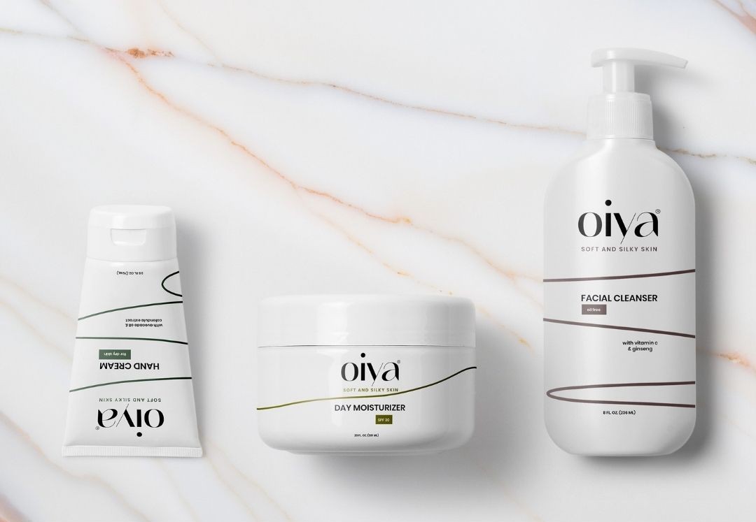 Oiya skincare packaging with facial cleanser, day moisturizer and hand cream in minimal white design on marble background